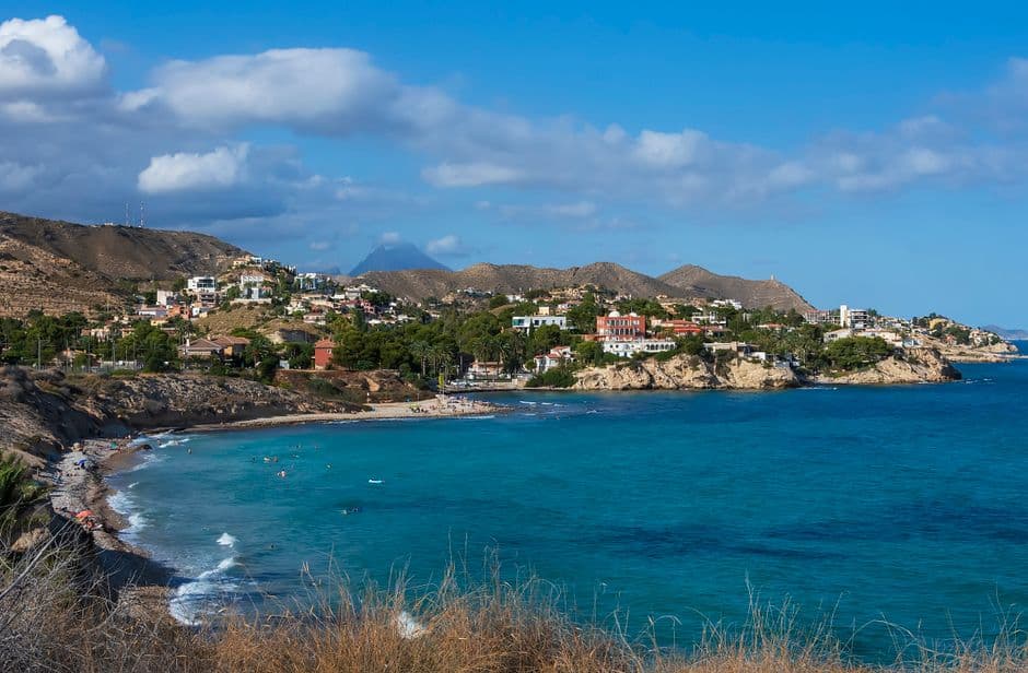 Playa de arena y aguas claras con casas al fondo, en el chat de El Campello
