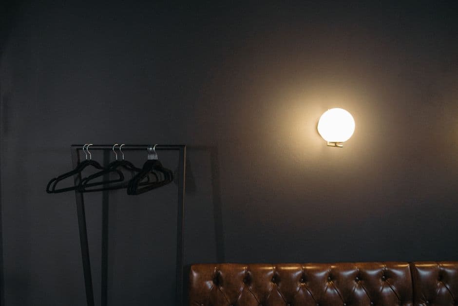 Luz gris en pared junto a perchas negras en rack, en el chat de BDSM