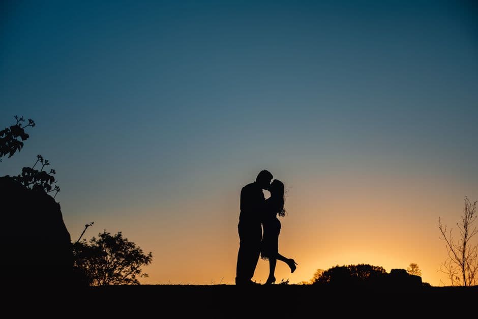 Pareja besándose en silueta contra un atardecer rojo, en la sala de chat de Sexualidad