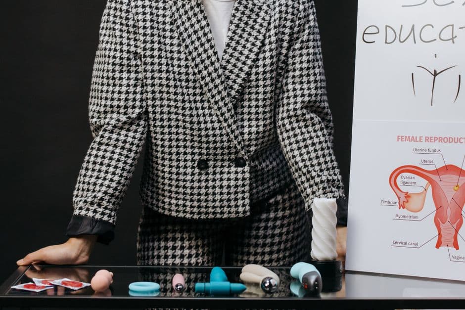 Persona traje apoyada mesa vidrio con juguetes plásticos, en la sala de chat de Educación sexual