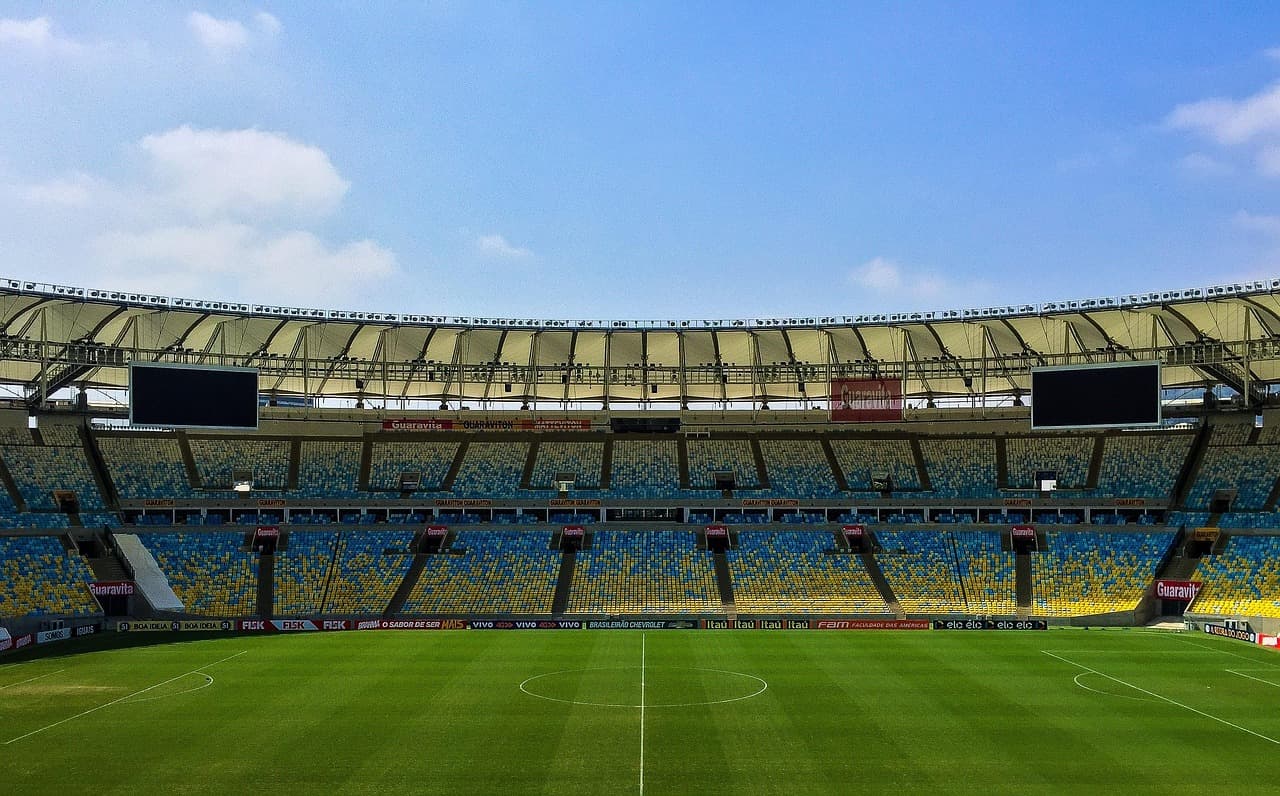 Gradas vacías al lado de un campo de fútbol verde, en el chat de Fútbol