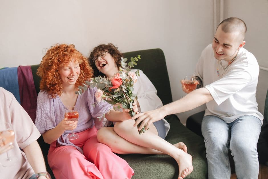 Un grupo de amigos sentados, bebiendo vino y riendo, en la sala de chat de Moda