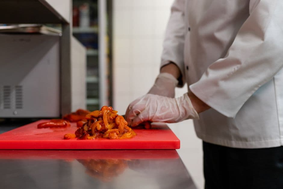 Chef concentrado picando verduras sobre una tabla de cortar, en la sala de chat de Recetas
