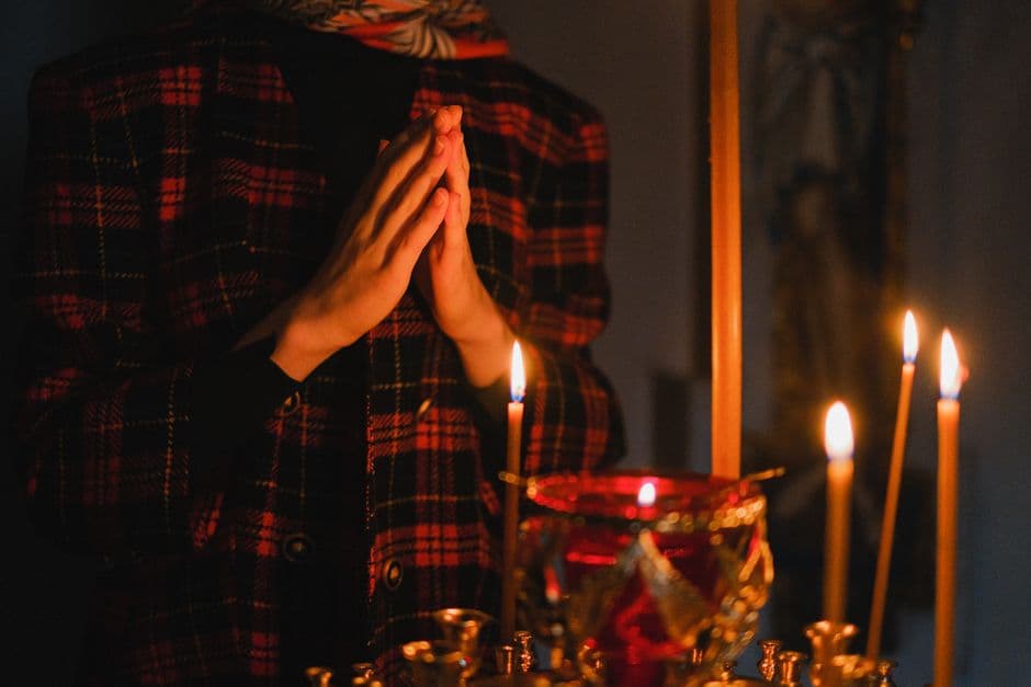 Persona con camisa cuadros rojos rezando ante velas, en la sala de chat de La Biblia