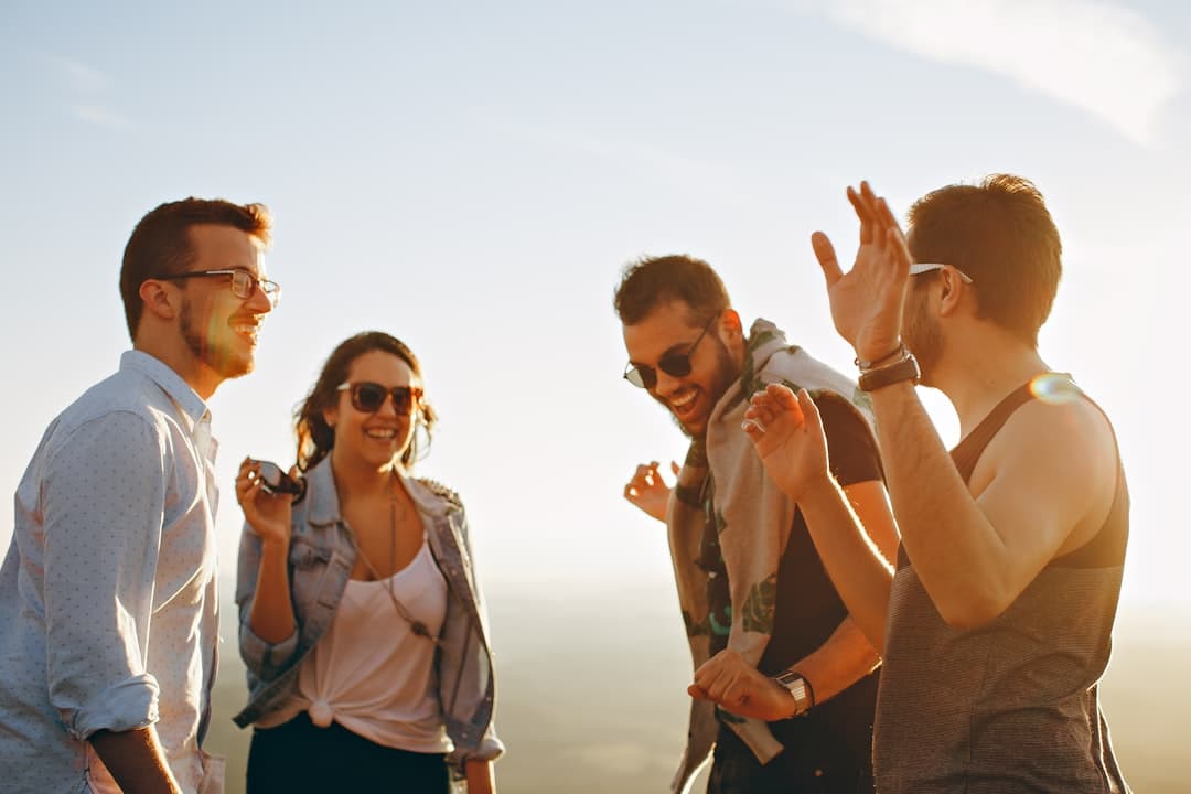 Cuatro amigos riendo bajo el sol, compartiendo alegría, en la sala de chat de Latinos