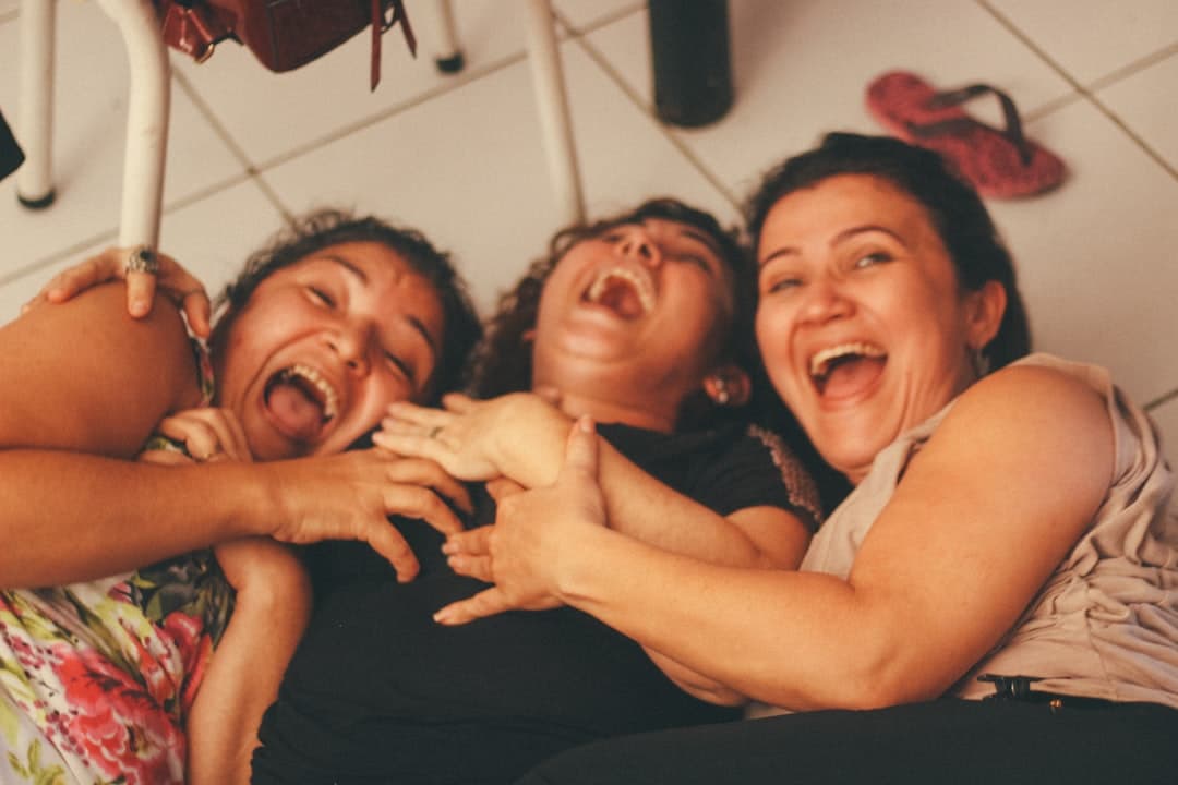 Mujeres riendo y sonriendo frente a una pared blanca, en la sala de chat de CPT