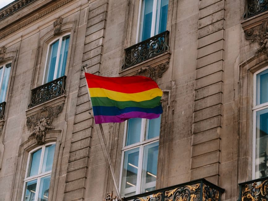 Bandera arcoíris ondeando junto a una ventana iluminada, en la sala de chat de Chueca Barcelona