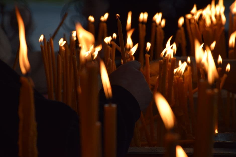 Manos entrelazadas sostienen una vela encendida con llama titilante, en la sala de chat de Iglesia