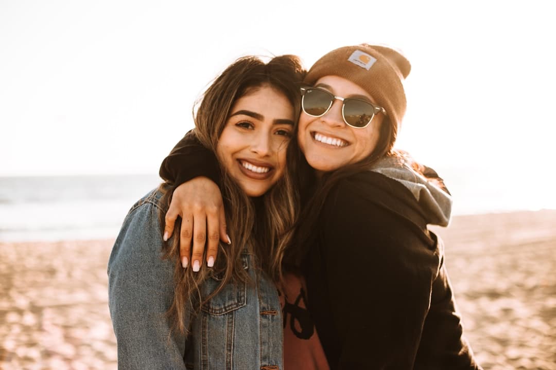 Dos mujeres se abrazan y sonríen en la playa, en la sala de chat de Badoo
