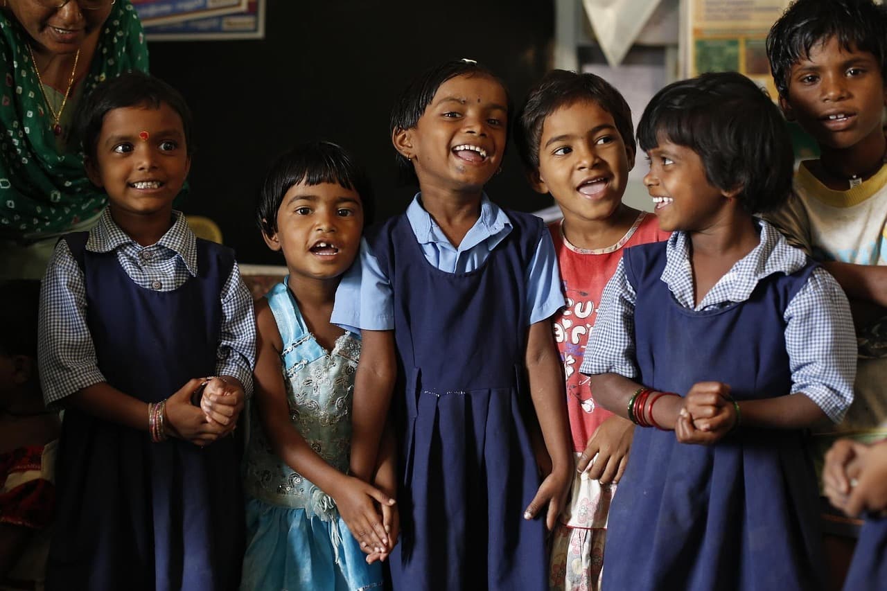 Niños indios sonríen y juegan en un aula colorida, en la sala de chat de Afroféminas