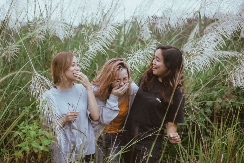Tres amigas se ríen y levantan copas, disfrutando juntas, en la sala de chat de Amigos
