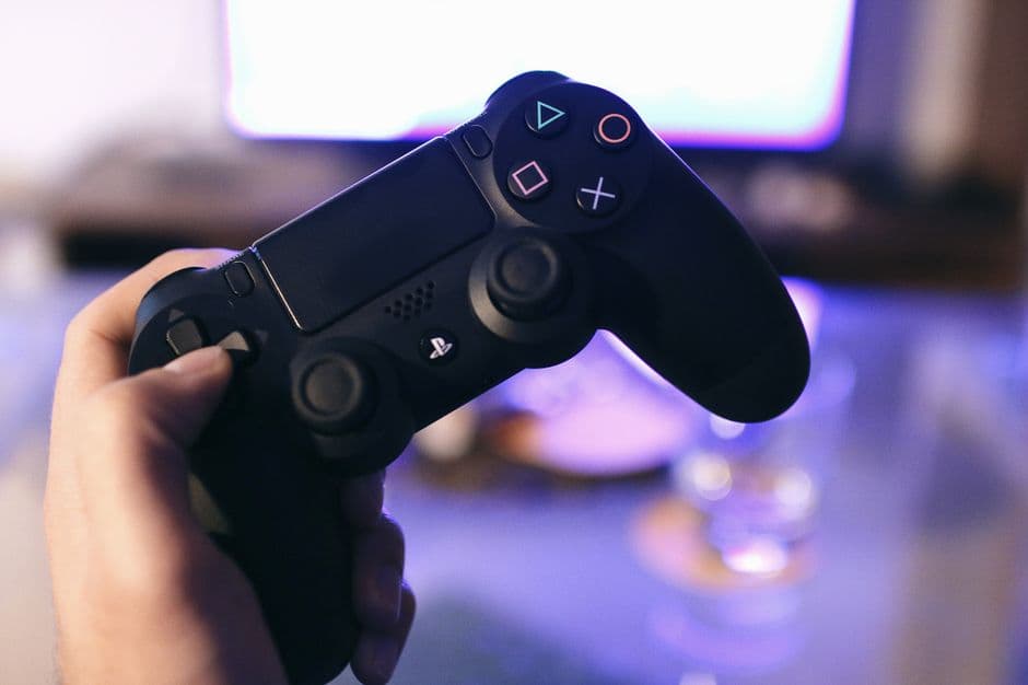 Mano sosteniendo un mando DualShock de PS4 de Sony, en la sala de chat de Magic