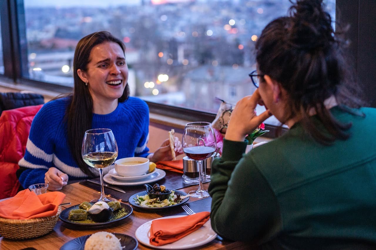 Mujeres riendo y brindando en un restaurante, en la sala de chat de Kaixo