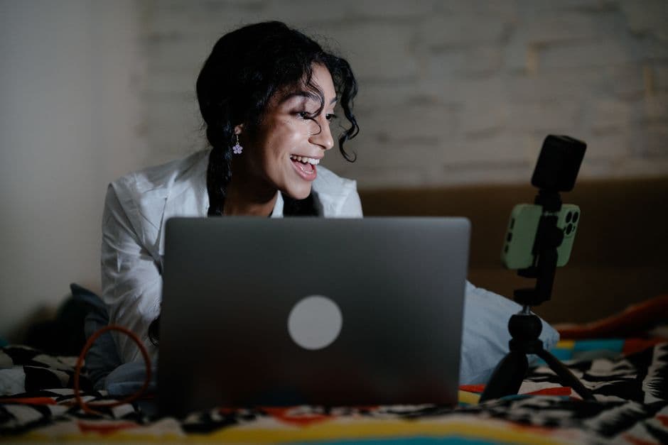 Mujer grabando video con su smartphone bajo luz tenue, en la sala de chat de Cam