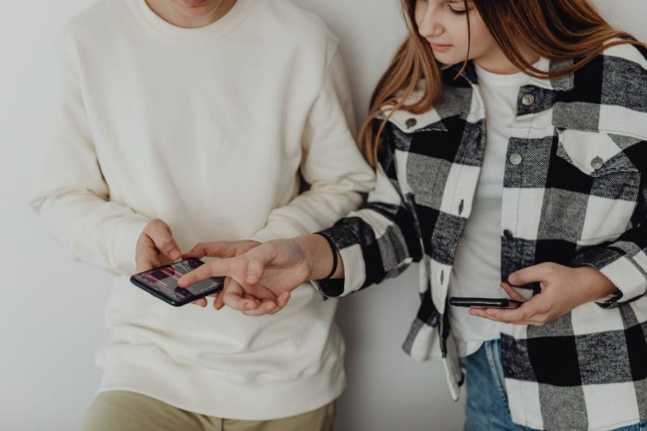 Pareja joven mirando sus teléfonos inteligentes mientras conversan, en la sala de chat de Telegram Madrid