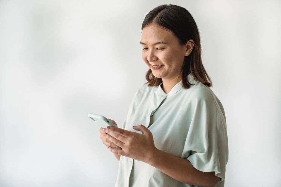 Una mujer sostiene un smartphone blanco, en la sala de chat de Telegram Uruguay