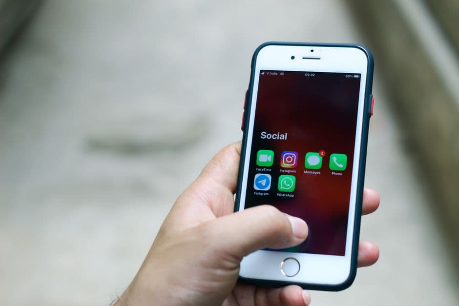 Persona sosteniendo un iPhone plateado, mirando la pantalla, en la sala de chat de Telegram Ecuador