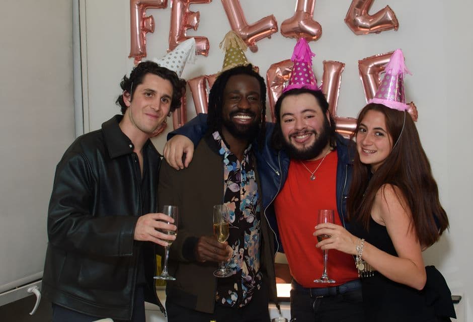Amigos sonrientes con sombreros de fiesta y champán, en la sala de chat de Onda Latina