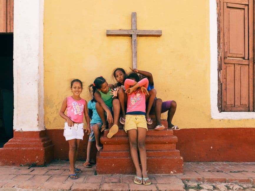 Niños latinos sonrientes frente a una iglesia blanca, en la sala de chat de Mi Punto