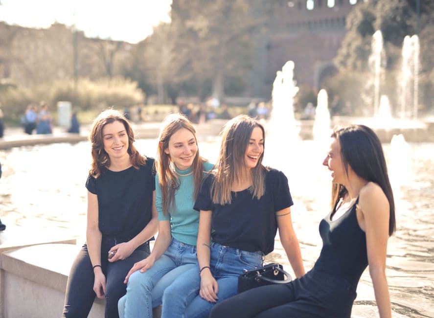 Mujeres riendo sentadas junto a fuente de agua, en la sala de chat de El Bar