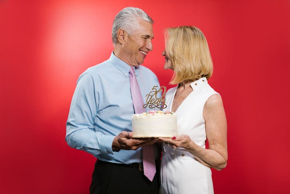 Una pareja mayor feliz sostiene un pastel, en la sala de chat de Amigos mayores