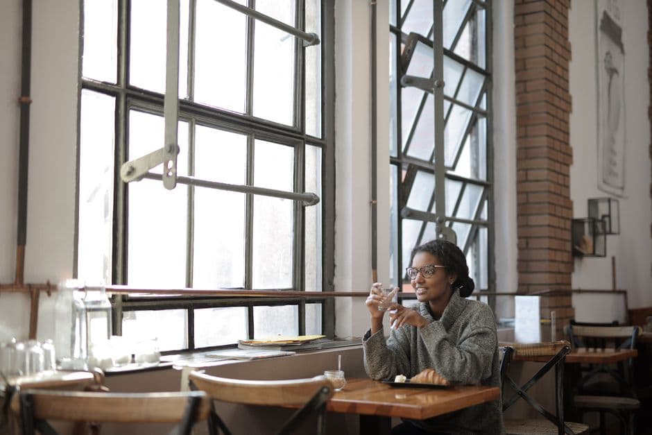 Mujer en suéter gris sentada junto a ventana de café en el chat de Divorciados
