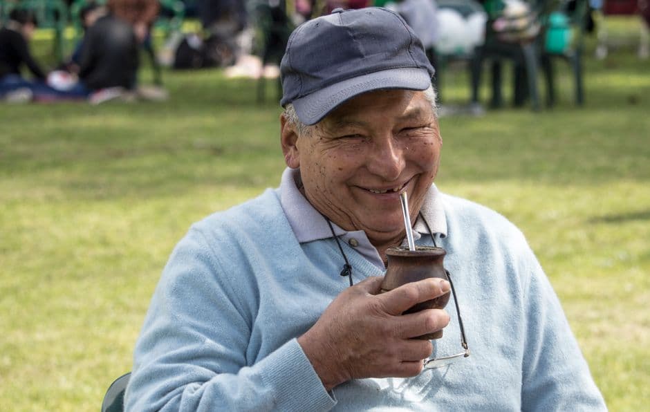 Hombre mayor sonriente con bebida en mano, en la sala de chat de Argentina más de 60