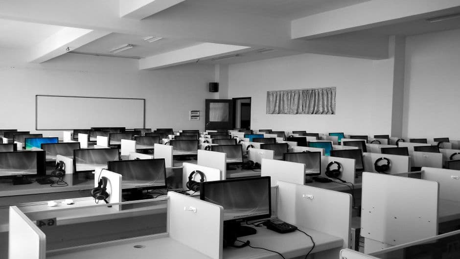 Cabinas de madera gris con computadoras vacías, en la sala de chat de Imperiochat