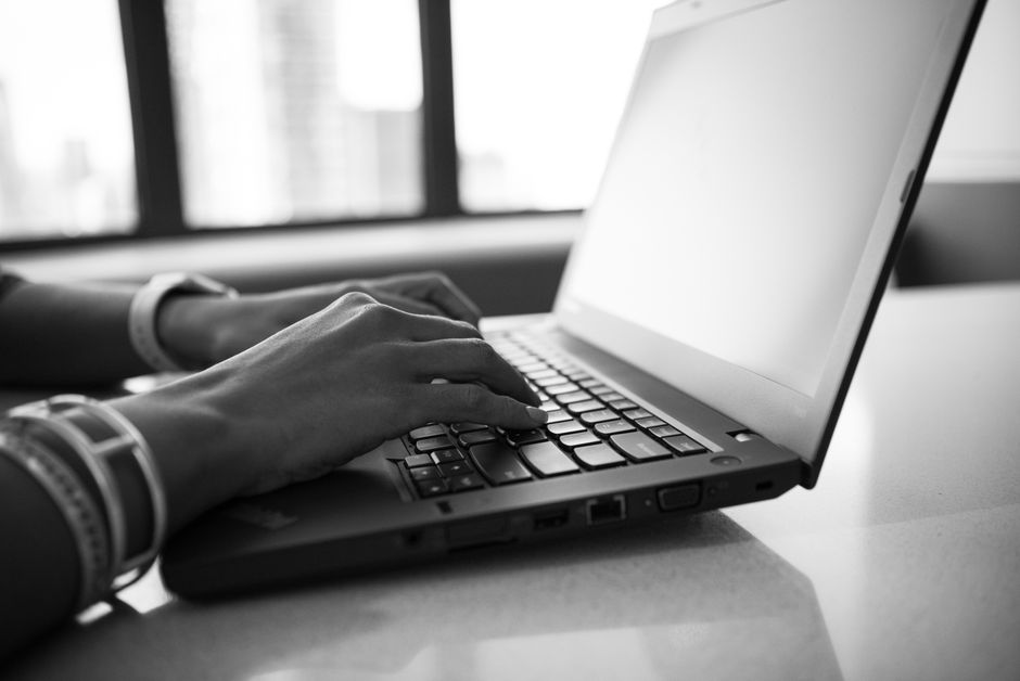 Mujer de perfil tecleando en laptop gris, concentrada, en la sala de chat de Sin registro