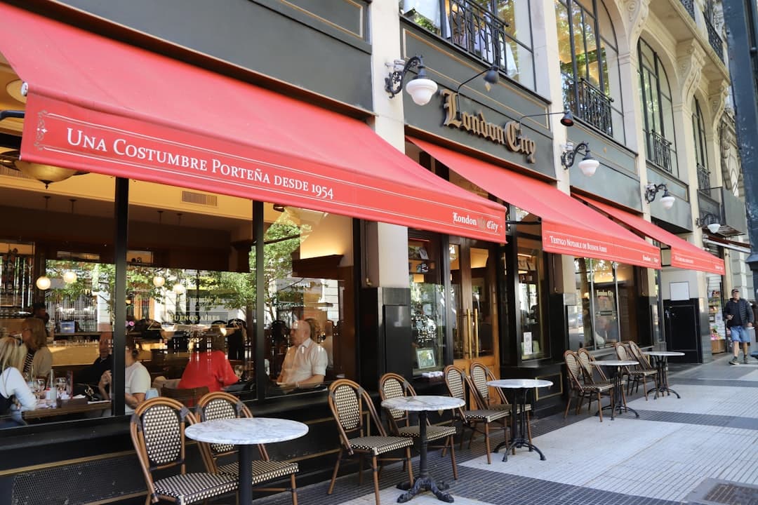 Café al aire libre con mesas, sillas y toldos rojos, en el chat de Paranachat