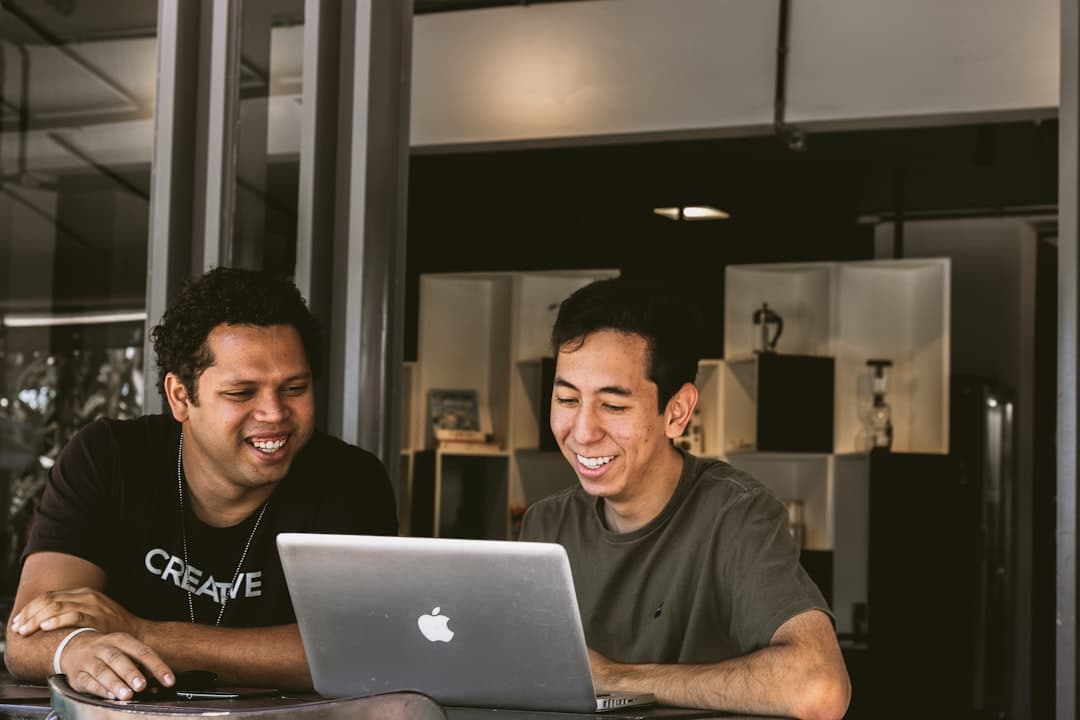 Dos hombres sonrientes mirando Macbook, en la sala de chat de Terra Chat Valencia