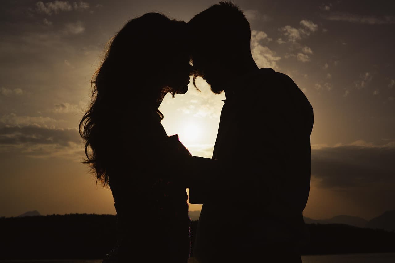 Silueta romántica de una pareja bajo corazones rojos, en la sala de chat de Cornudos irc