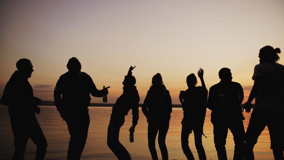 Silhouette de amigos disfrutando el atardecer junto al lago, en la sala de chat de Trío