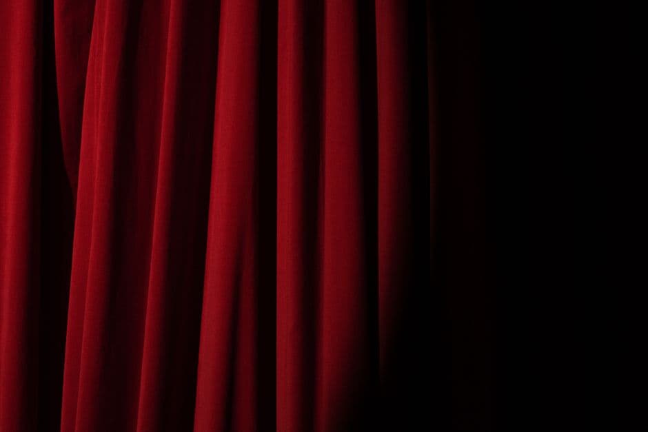 Cortina roja iluminada por un foco bajo, creando ambiente teatral, en el chat de Porno